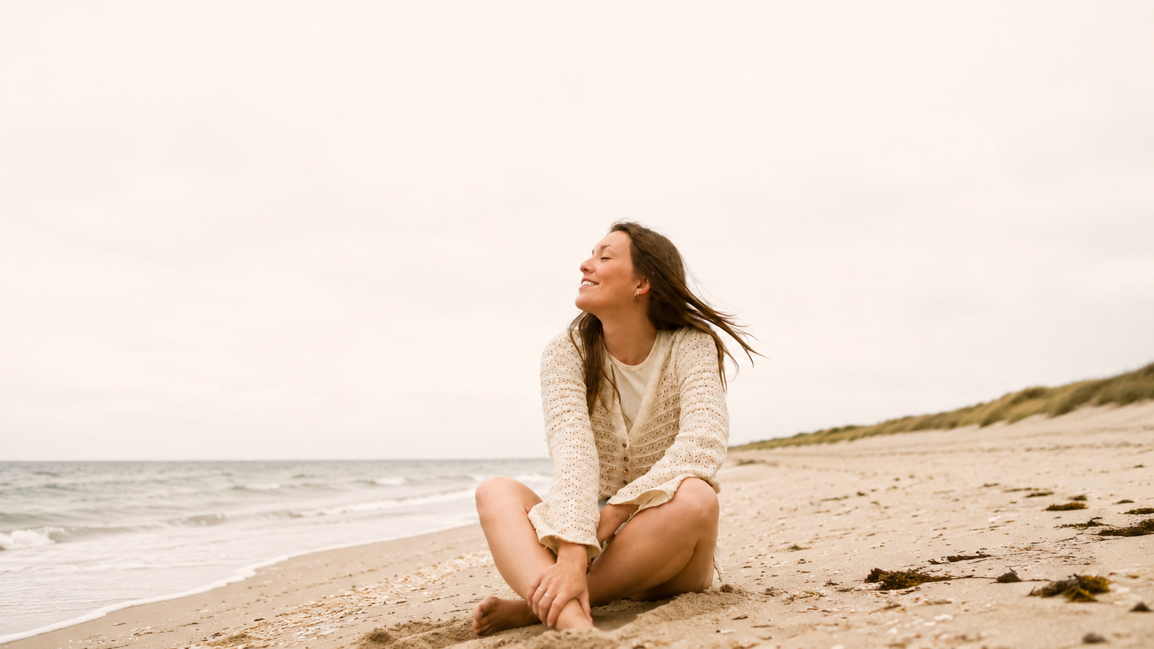 Woman sitting on a quiet beach at golden hour