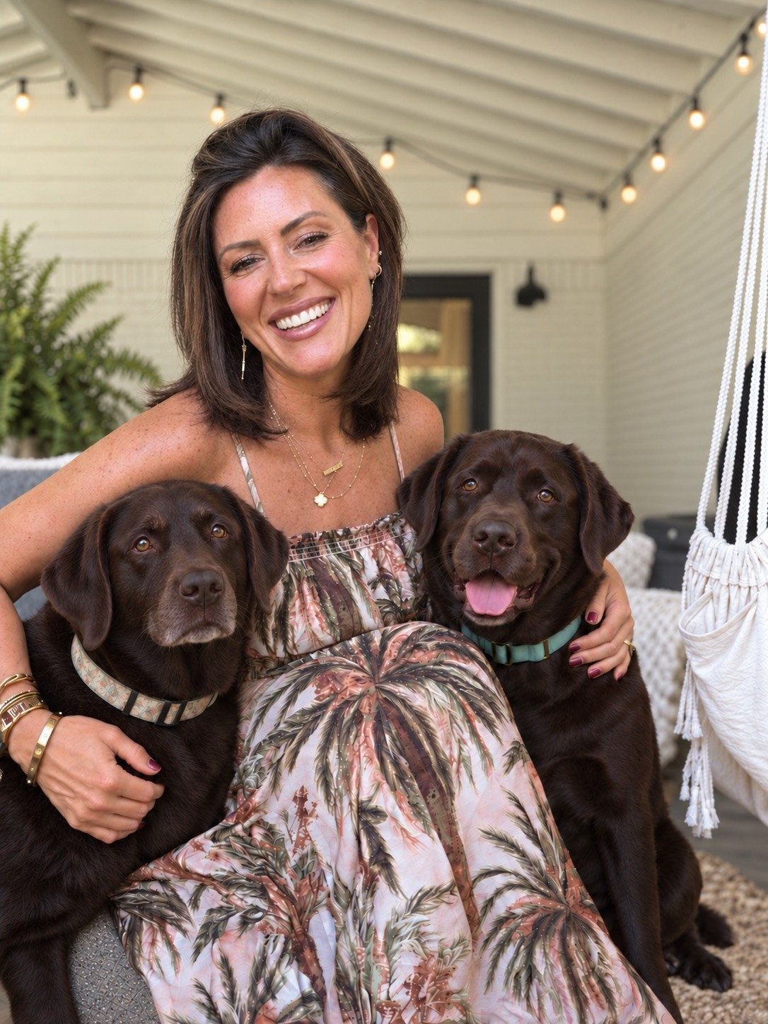 Mandy Lea sitting on a porch with her two chocolate Labradors